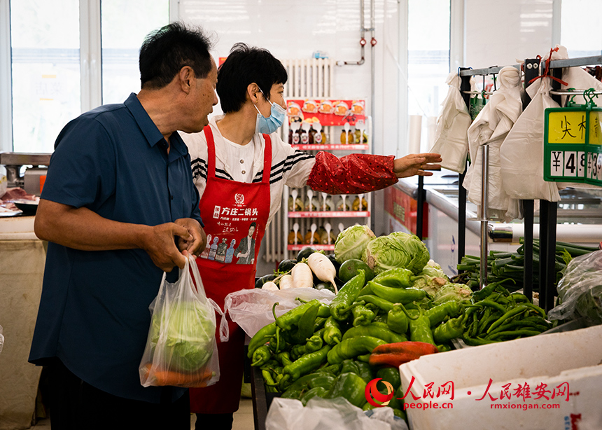 菜店內，工作人員正在為顧客提供幫助。出門就是菜店，吃飯不發愁，成為容東片區居民的日常。人民網?宋燁文攝