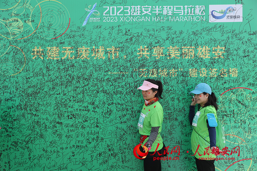 2023雄安半程馬拉松活動(dòng)現(xiàn)場(chǎng)，雄安新區(qū)生態(tài)環(huán)境局宣傳、倡導(dǎo)無(wú)廢城市展板吸引參賽選手一一簽名。人民網(wǎng) 李兆民攝