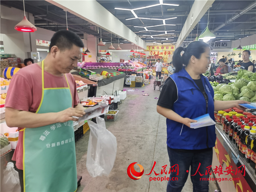 普法活動進市場。安新縣委政法委供圖